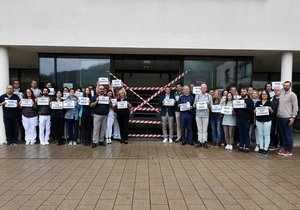 Mitarbeitende der Diakonie-Klinik protestieren vor dem Klinikgebäude.
